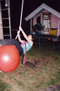 Full length of young woman playing on rope swing