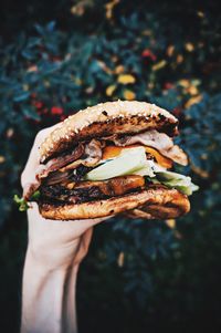 Close-up of hand holding burger outdoors