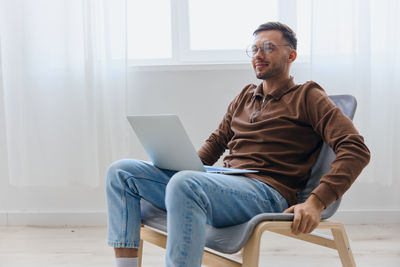 Portrait of man using laptop while sitting on sofa at home