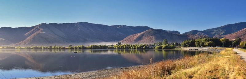 Scenic view of lake and mountains against clear blue sky