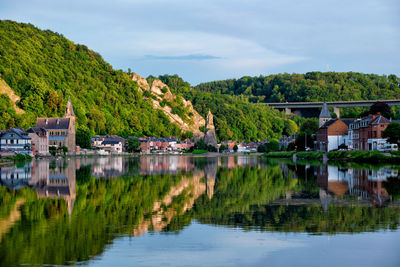 Scenic view of lake by trees and houses against sky