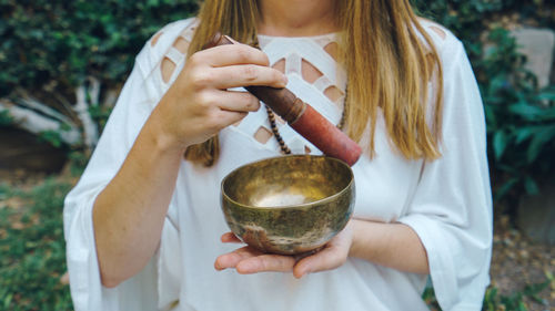 Midsection of woman holding tibetan singing bowl