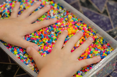 High angle view of person hand on multi colored candies