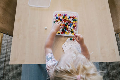 Directly above shot of girl playing pegboard game on table