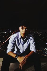 Young man sitting in city at night