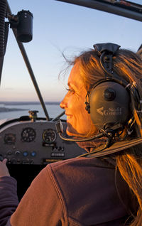 Smiling woman wearing headset while sitting in helicopter