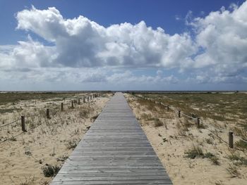 View of boardwalk on landscape against sky