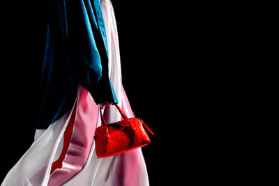 Midsection of woman holding gift against black background