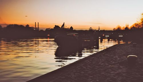 Silhouette of boats in river during sunset