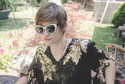 Young woman wearing sunglasses standing at yard on sunny day