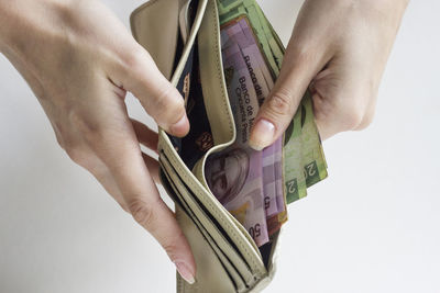 Close-up of hand holding paper over white background