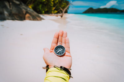 Close-up of hand holding navigational compass at beach