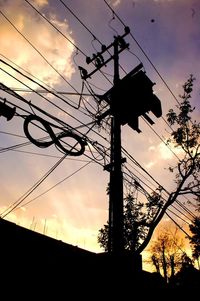 Low angle view of electricity pylon against cloudy sky