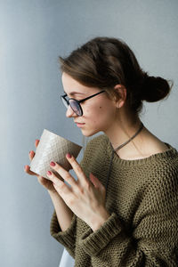 Millennial brown-haired girl in glasses drinking tea with cakes alone