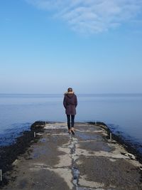 Rear view of man standing on sea against clear sky