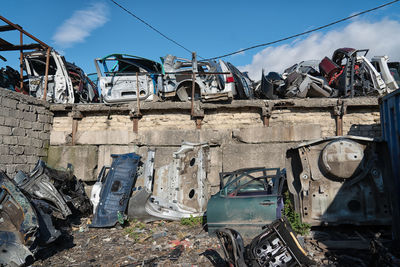 Abandoned cars by metal against sky