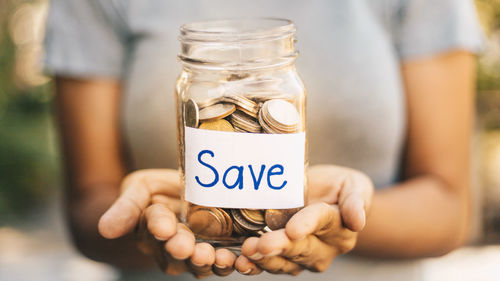 Close-up of woman hand holding jar with text