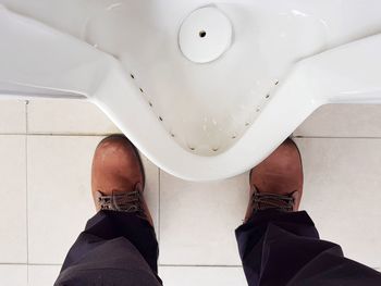 Low section of man standing by toilet bowl in public restroom