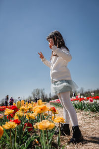 Girl in white dress standing at tulip field in the farm