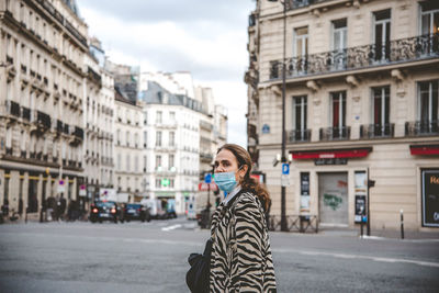 Portrait of woman standing on road against buildings