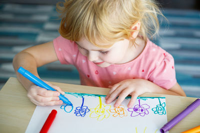 Little girl drawing with colored markers.