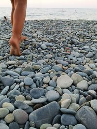 Low section of person on pebbles at beach