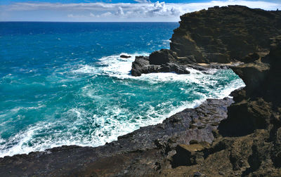 Rock formation on sea shore against sky