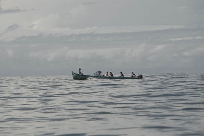 People on boat in sea against sky