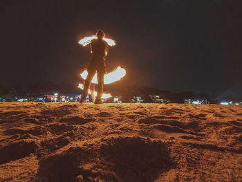 Rear view of woman standing on beach against sky at night