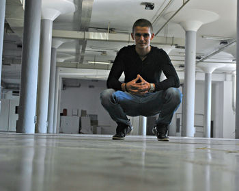 Portrait of man crouching in corridor