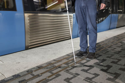 Man with white cane standing at metro station