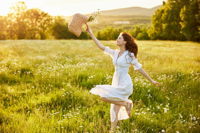 Young woman with arms raised standing on grassy field