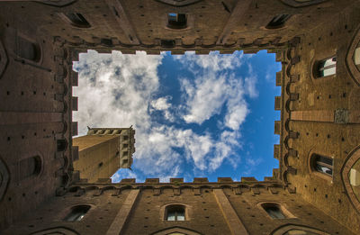 Low angle view of torre del mangia against blue sky