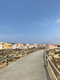 Footpath amidst buildings in city against sky