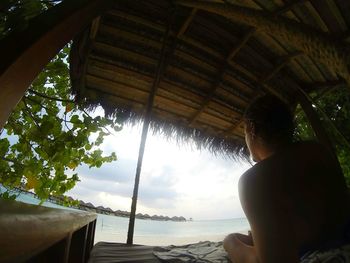 Woman on beach by window against sky