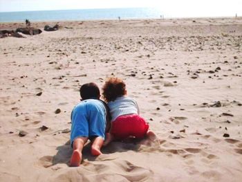 Rear view of friends sitting on beach