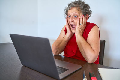 Young woman using mobile phone while sitting on table