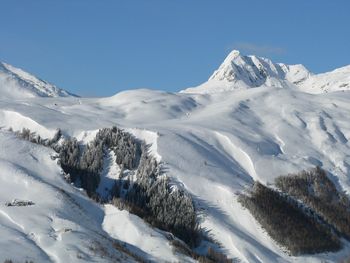 Scenic view of snow covered mountains against clear blue sky