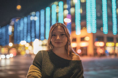 Fashionable young woman in city at night