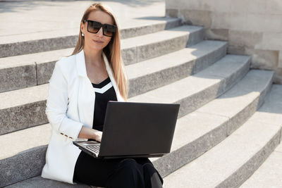 Midsection of woman using mobile phone while sitting on staircase