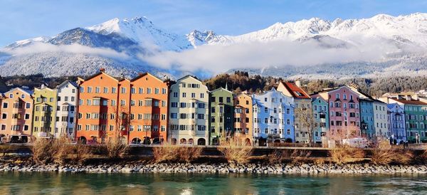 Buildings by snowcapped mountains against sky during winter