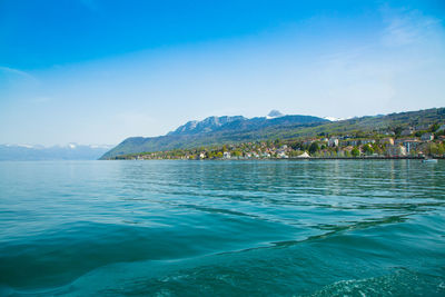 Scenic view of sea and mountains against blue sky