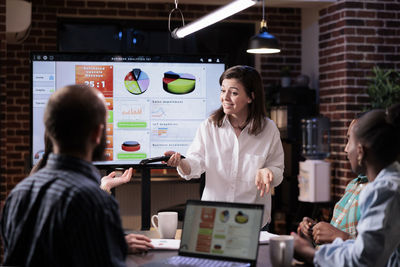 Businesswoman discussing with colleague at desk in office