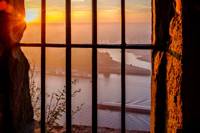 Sea seen through window during sunset