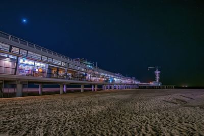 Pier at sandy beach against sky during night at scheveningen