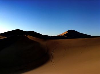 Scenic view of desert against clear blue sky