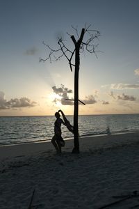 Silhouette woman on beach against sky during sunset