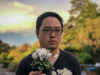 Portrait of young man holding eyeglasses