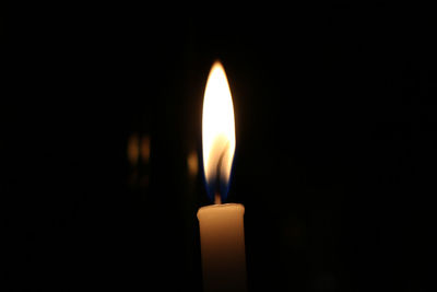 Close-up of burning candle against black background