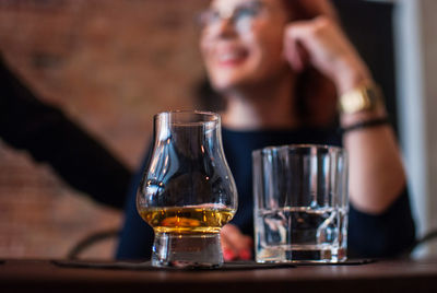 Close-up of scotch whiskey in glass with people in background at bar